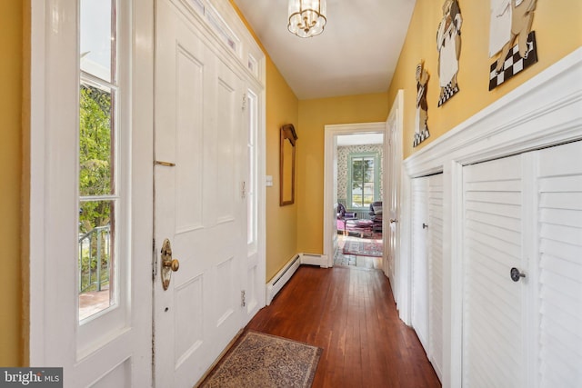 doorway with a chandelier, baseboard heating, and dark wood finished floors