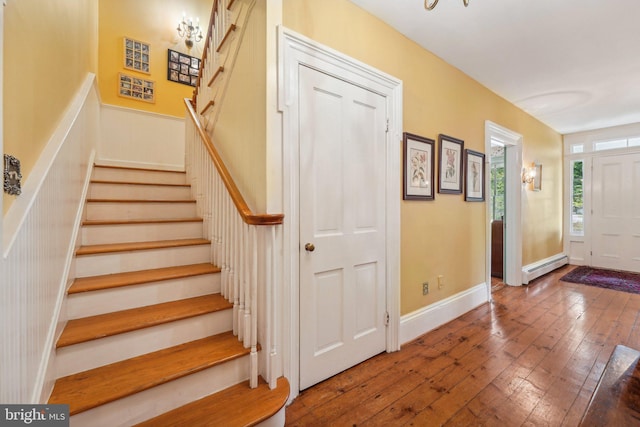 entryway featuring a baseboard radiator, hardwood / wood-style floors, baseboards, and stairs