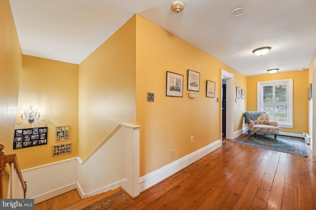 corridor featuring baseboards, a wainscoted wall, an upstairs landing, and hardwood / wood-style flooring