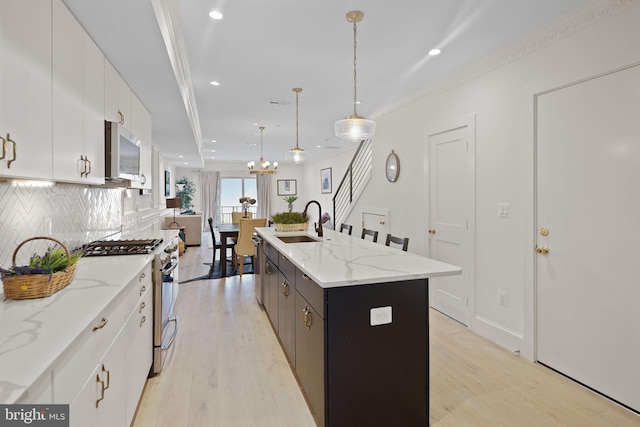 kitchen with a center island with sink, white cabinetry, pendant lighting, and stainless steel appliances