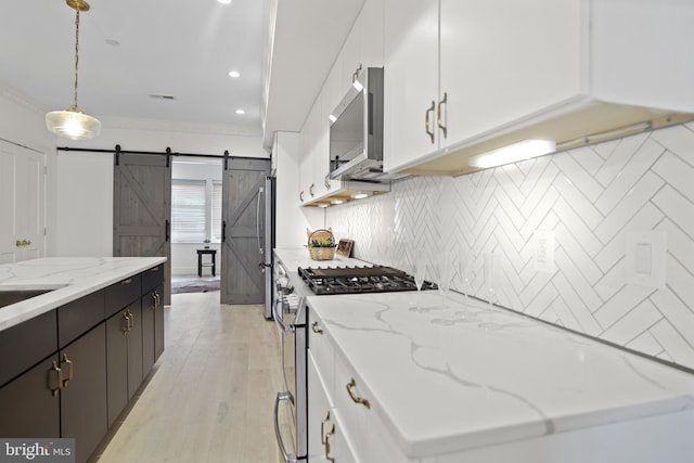 kitchen with a barn door, white cabinetry, appliances with stainless steel finishes, and pendant lighting