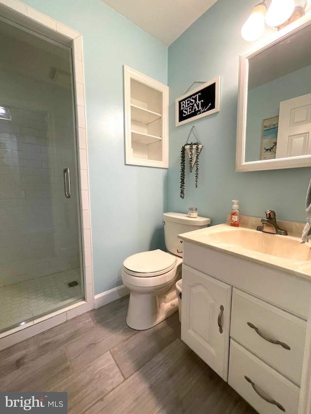 bathroom with hardwood / wood-style floors, an enclosed shower, vanity, and toilet