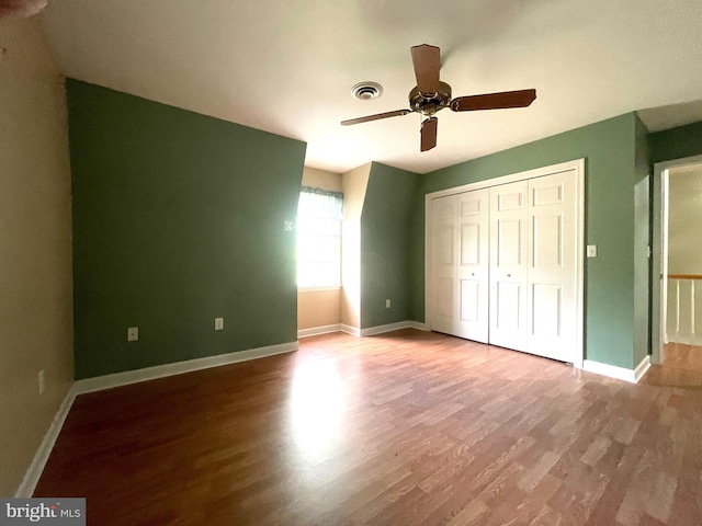 unfurnished bedroom featuring wood-type flooring, a closet, and ceiling fan