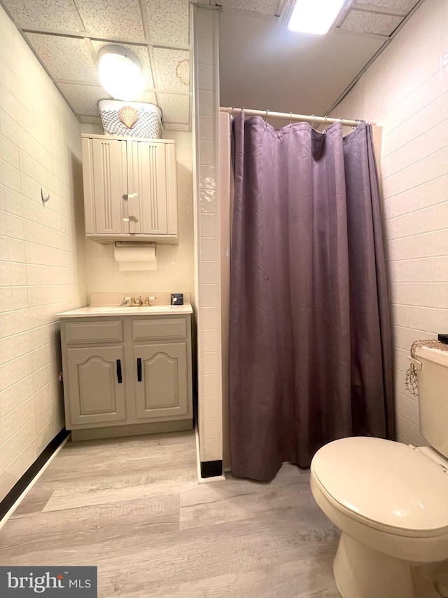 bathroom with hardwood / wood-style flooring, a paneled ceiling, a shower with shower curtain, vanity, and toilet