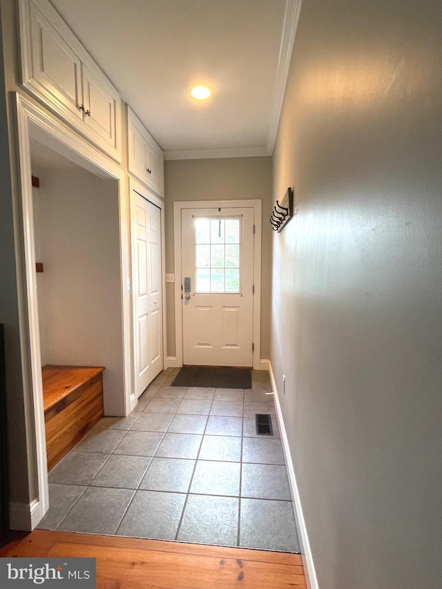 entryway featuring ornamental molding and light tile patterned floors