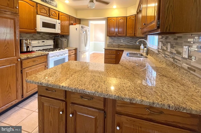 kitchen featuring light stone counters, ceiling fan, light tile patterned flooring, tasteful backsplash, and white appliances