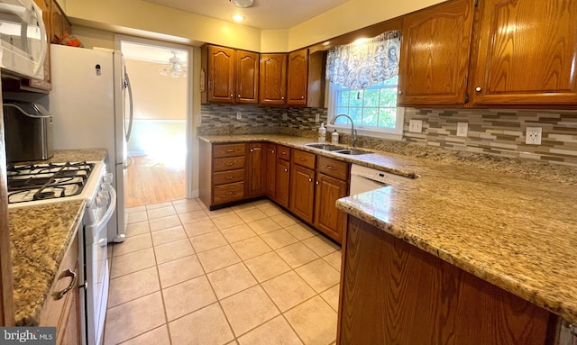 kitchen with light stone counters, backsplash, white appliances, light tile patterned floors, and sink