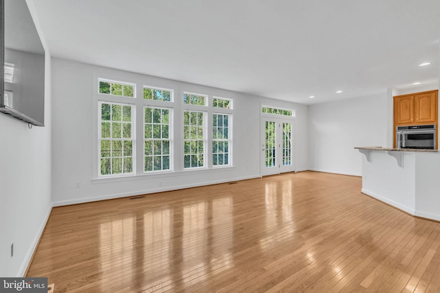 unfurnished living room with light hardwood / wood-style floors and french doors