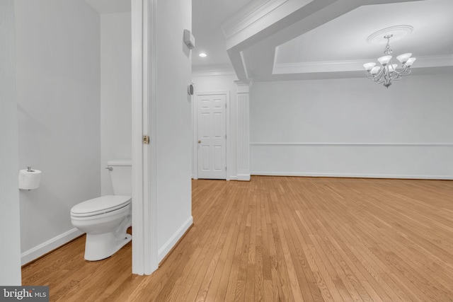 bathroom with a chandelier, crown molding, hardwood / wood-style floors, and toilet