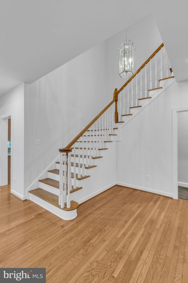 stairs with a notable chandelier and wood-type flooring