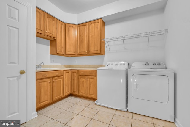 laundry area featuring separate washer and dryer, sink, light tile patterned floors, and cabinets