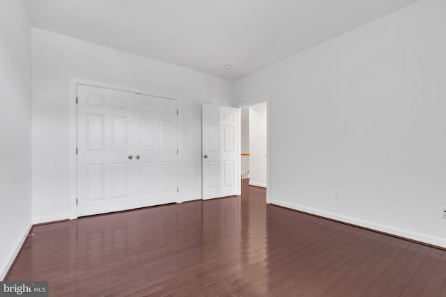 unfurnished bedroom featuring a closet and dark wood-type flooring