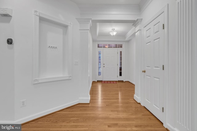 interior space featuring light wood-type flooring, crown molding, and decorative columns