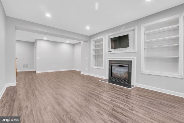 unfurnished living room featuring hardwood / wood-style flooring and built in features