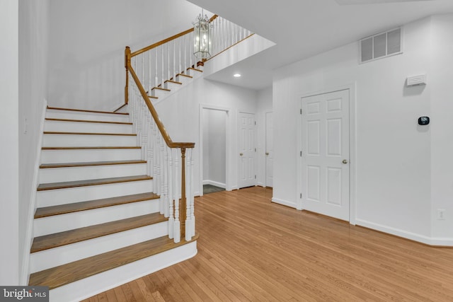 staircase featuring wood-type flooring and an inviting chandelier