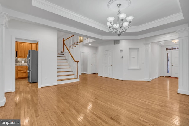 unfurnished living room with ornamental molding, light hardwood / wood-style flooring, a chandelier, and a raised ceiling