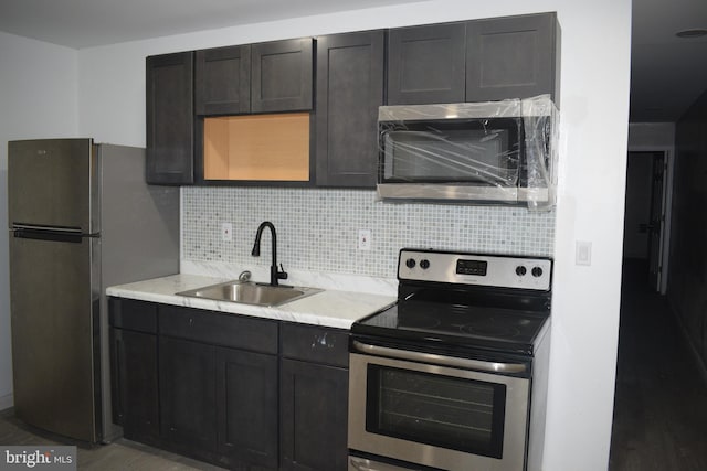 kitchen with appliances with stainless steel finishes, hardwood / wood-style floors, sink, and decorative backsplash