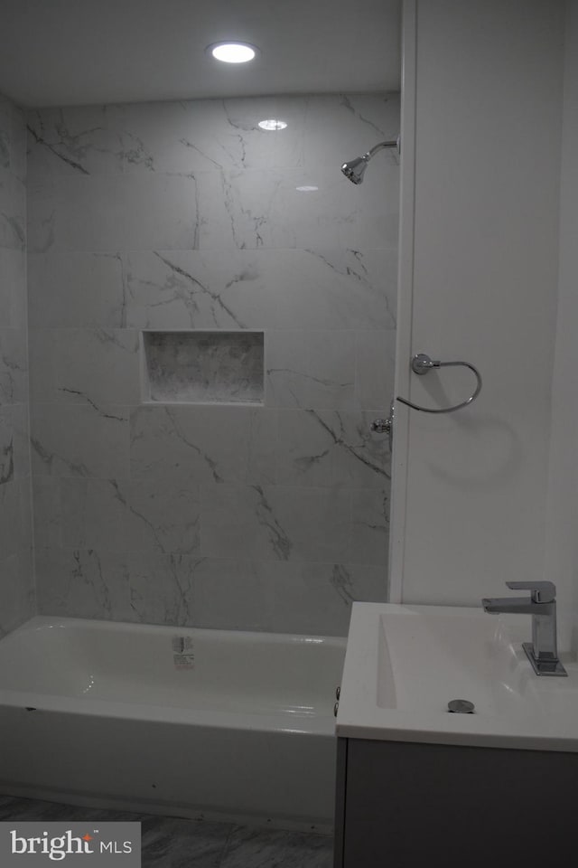 bathroom featuring tiled shower / bath combo and vanity