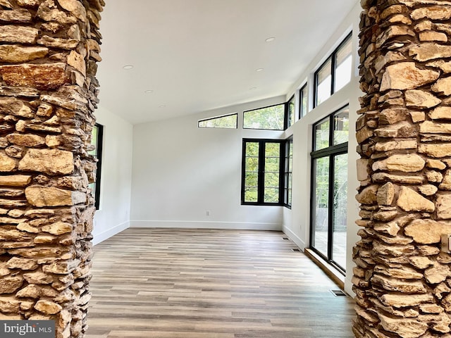 unfurnished room featuring a high ceiling and light hardwood / wood-style floors