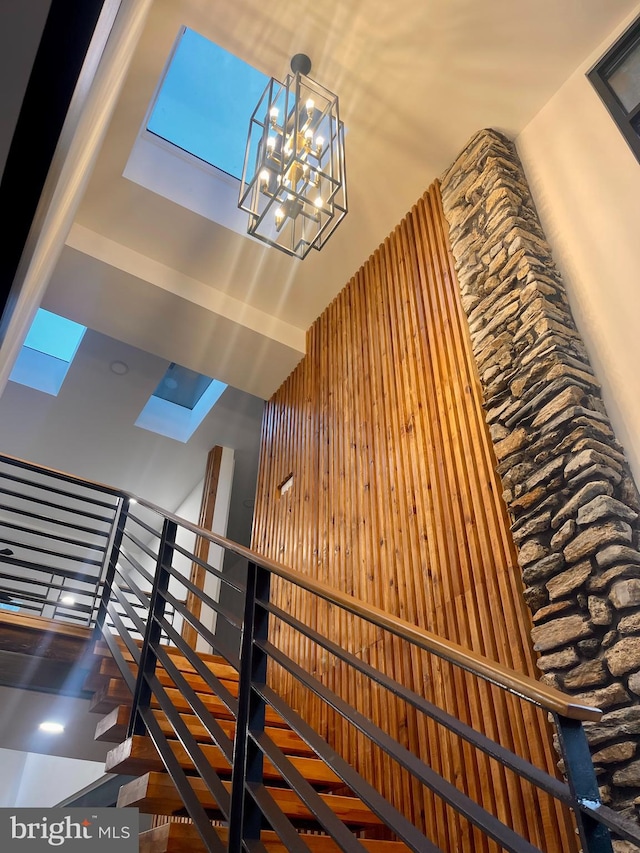 stairs featuring wood walls and a notable chandelier