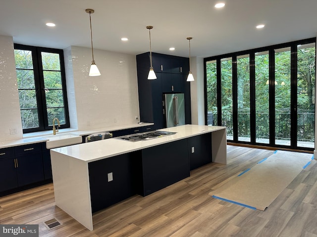 kitchen with stainless steel appliances, a center island, light hardwood / wood-style floors, and hanging light fixtures