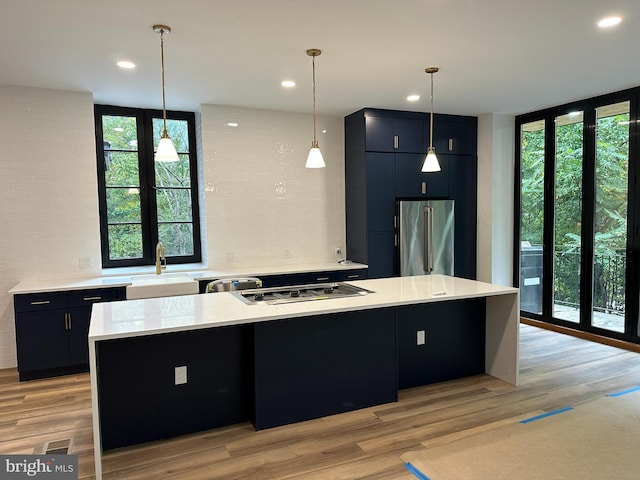 kitchen with appliances with stainless steel finishes, a center island, sink, and hanging light fixtures