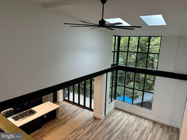 stairs with a healthy amount of sunlight, a skylight, high vaulted ceiling, and wood-type flooring