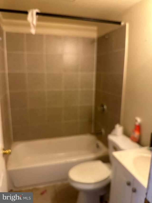 full bathroom featuring vanity, tiled shower / bath combo, and toilet