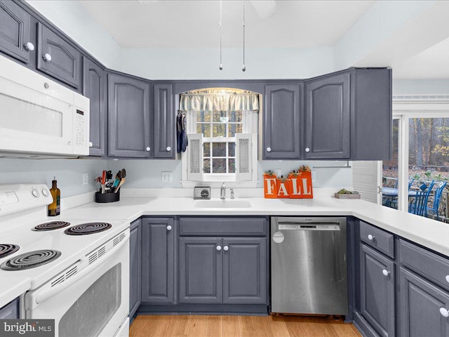 kitchen featuring a healthy amount of sunlight, sink, white appliances, and light hardwood / wood-style flooring