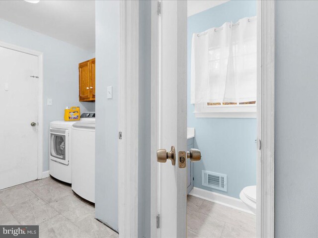 clothes washing area featuring washing machine and dryer and cabinets