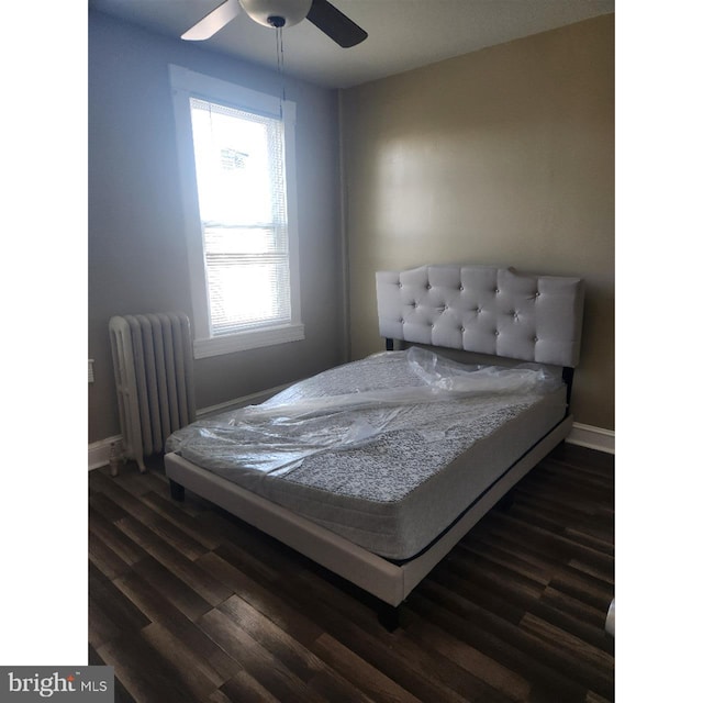 bedroom featuring dark wood-type flooring, radiator heating unit, and ceiling fan