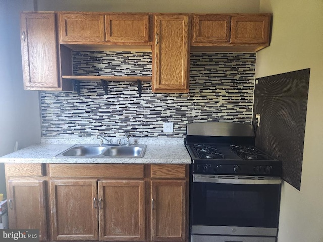 kitchen with stainless steel gas stove, sink, and decorative backsplash