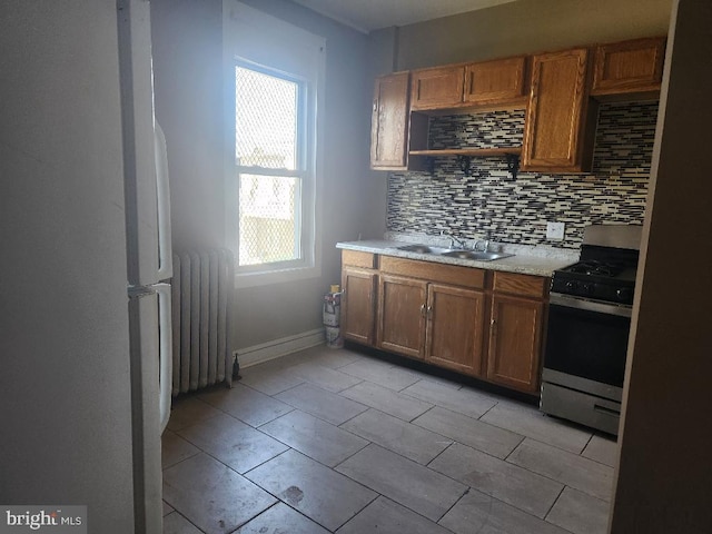 kitchen with white fridge, radiator, stainless steel stove, and a healthy amount of sunlight