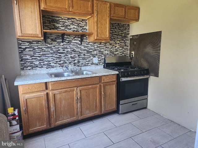 kitchen with backsplash, stainless steel gas range, and sink