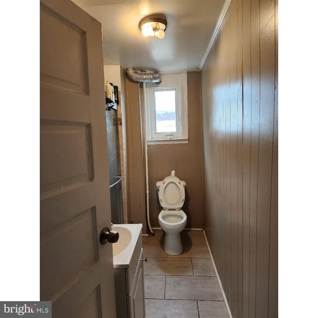 bathroom with wooden walls, tile patterned floors, vanity, and toilet