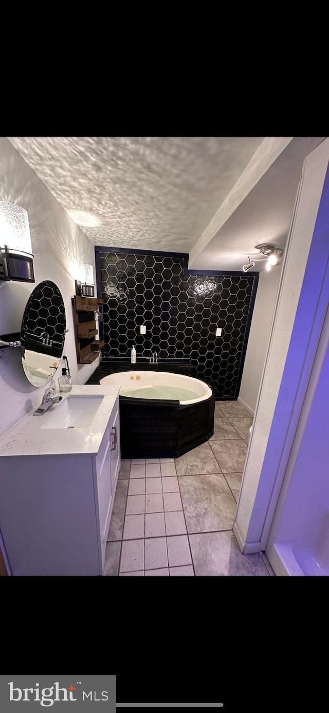 bathroom with a textured ceiling, vanity, a tub, and tile patterned floors