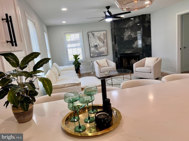 living room with a premium fireplace, baseboards, a ceiling fan, and recessed lighting