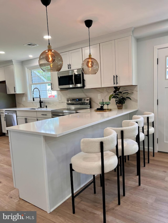 kitchen with appliances with stainless steel finishes, a sink, a breakfast bar, and tasteful backsplash