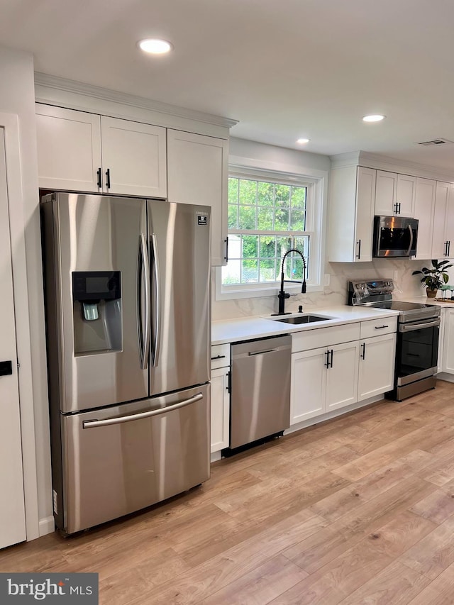 kitchen with light wood-style floors, stainless steel appliances, a sink, and light countertops