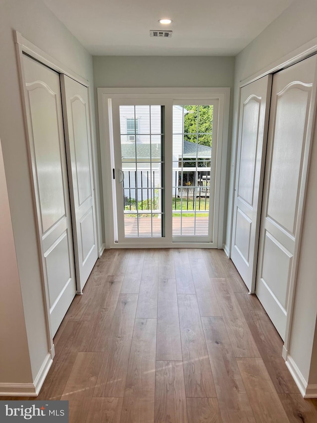 doorway to outside with baseboards, visible vents, and wood finished floors