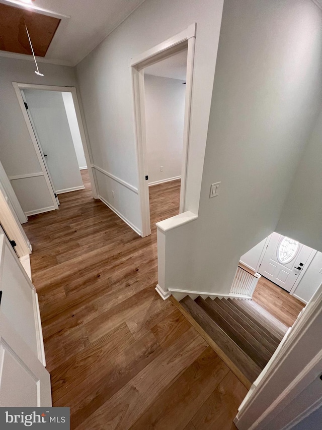 staircase featuring attic access, baseboards, and wood finished floors