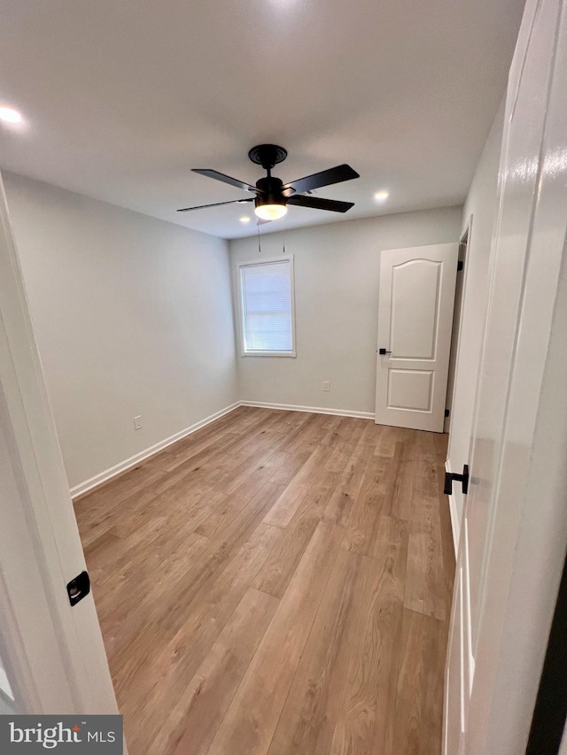 empty room with light wood-style floors, ceiling fan, and baseboards