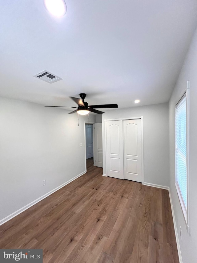 unfurnished bedroom featuring a closet, visible vents, a ceiling fan, wood finished floors, and baseboards