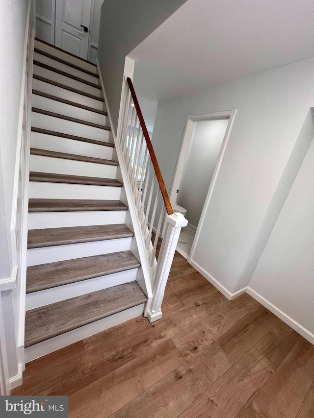 stairway with baseboards and wood finished floors