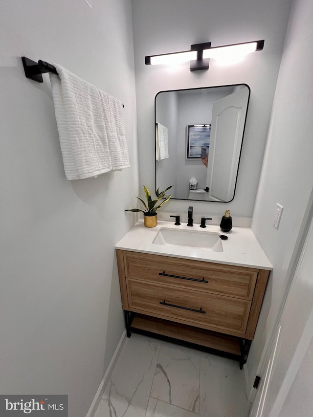 bathroom with marble finish floor, toilet, vanity, and baseboards