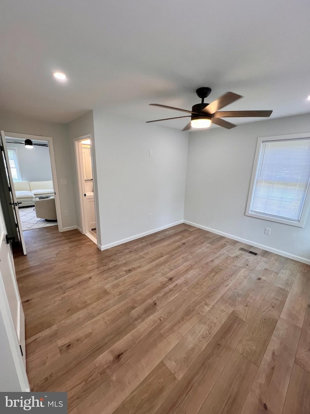 empty room featuring visible vents, ceiling fan, baseboards, and wood finished floors