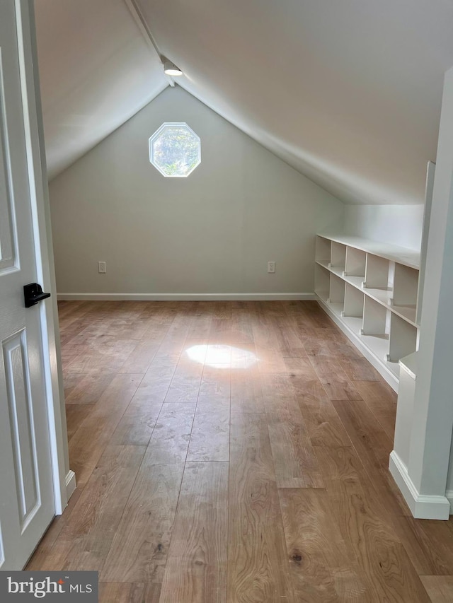 additional living space with vaulted ceiling, wood finished floors, and baseboards