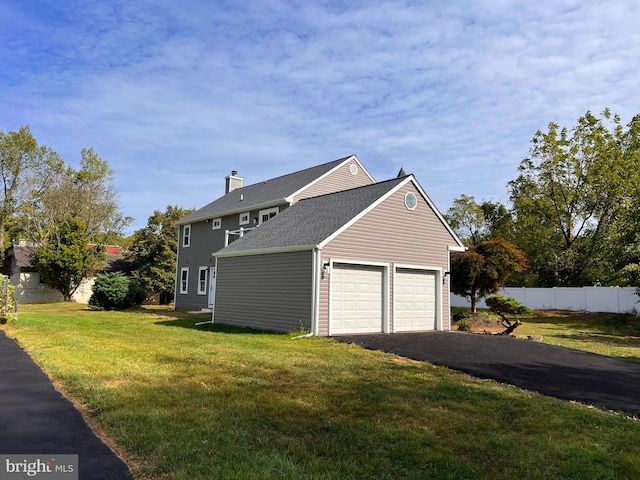 view of side of home featuring a garage, a shingled roof, fence, driveway, and a yard