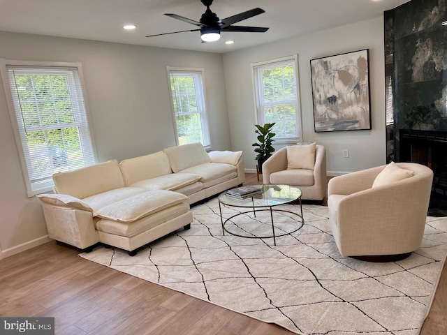 living area with recessed lighting, a tiled fireplace, baseboards, and wood finished floors