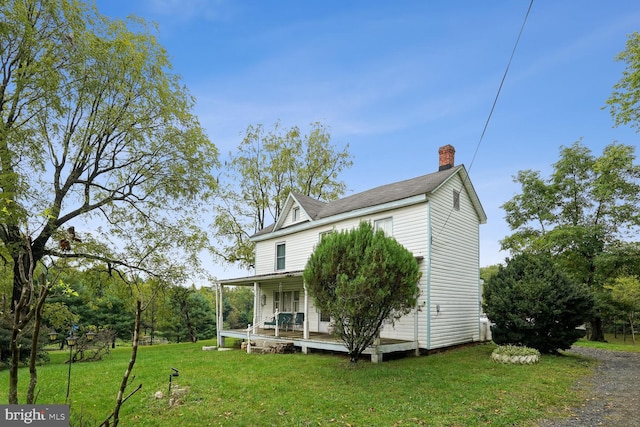 back of property with a lawn and a porch